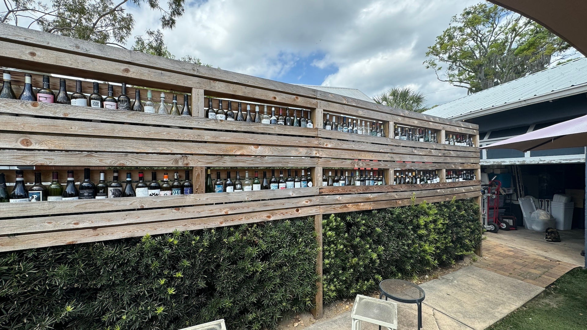 Outdoor area with greenery and shelves filled with wine